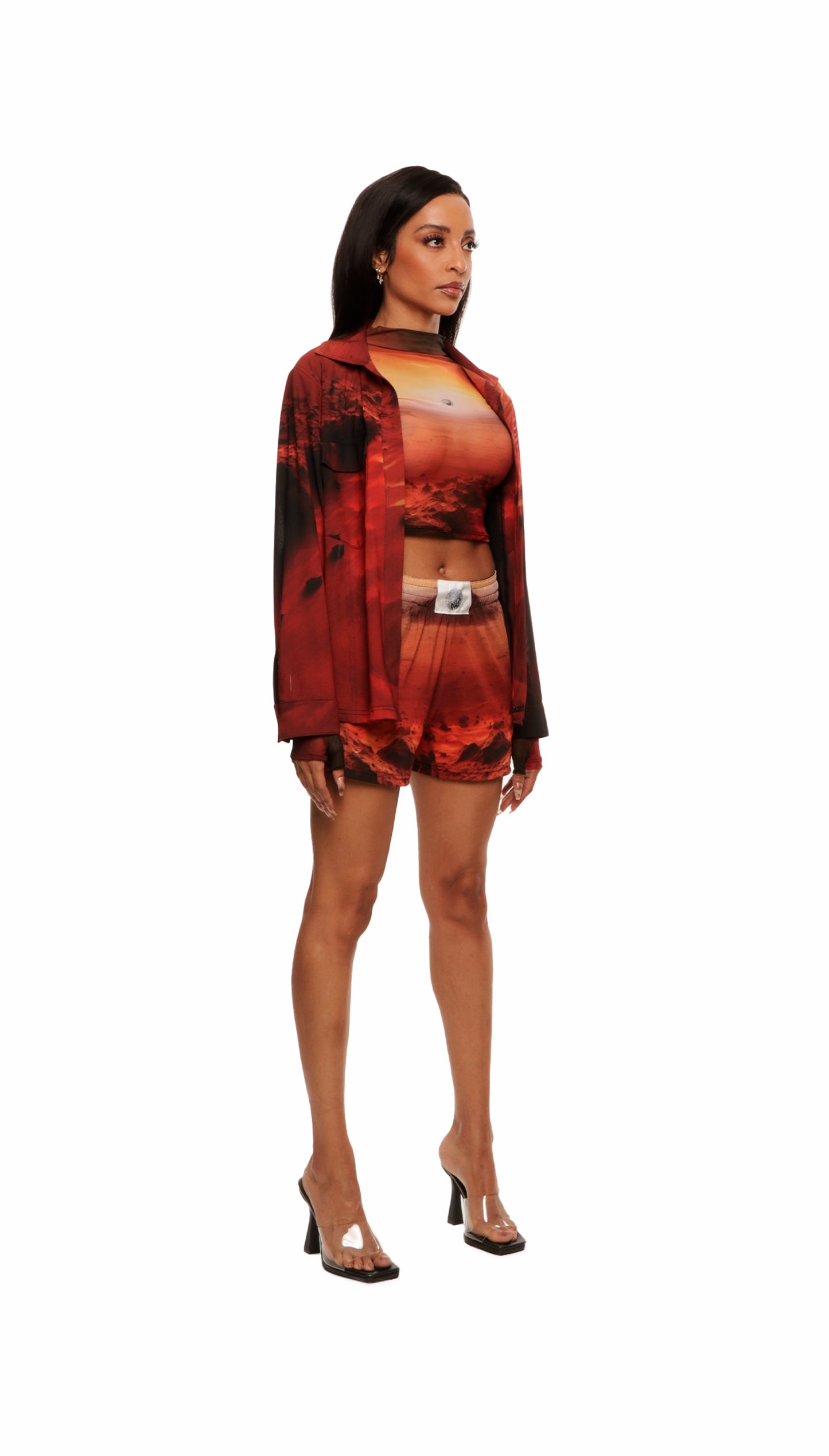 Woman who looks like Beyoncé or Aaliyah wears a cosmic sunset printed long sleeve button up shirt with snaps, side view