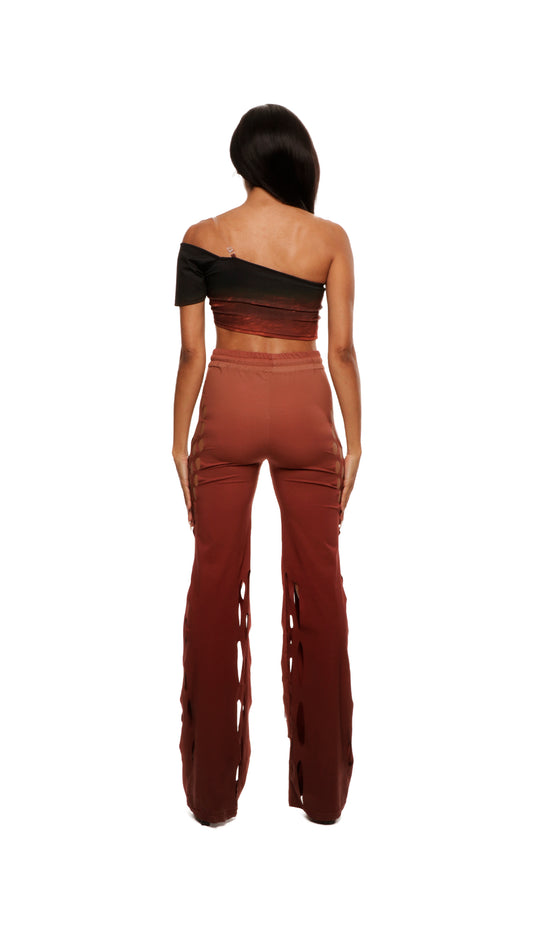Woman who looks like Beyoncé or Aaliyah wears gradient brown toned bottoms or pants with cutout details on the sides, back view