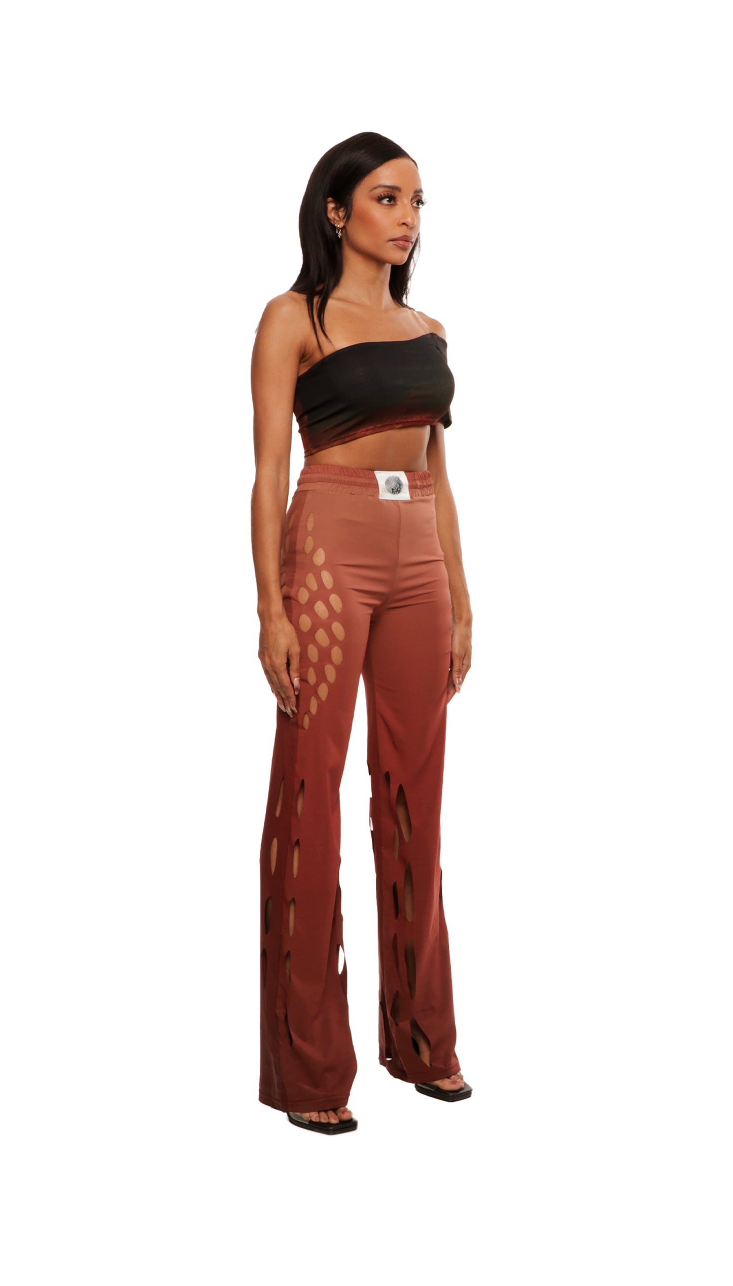 Woman who looks like Beyoncé or Aaliyah wears gradient brown toned bottoms or pants with cutout details on the sides, side view