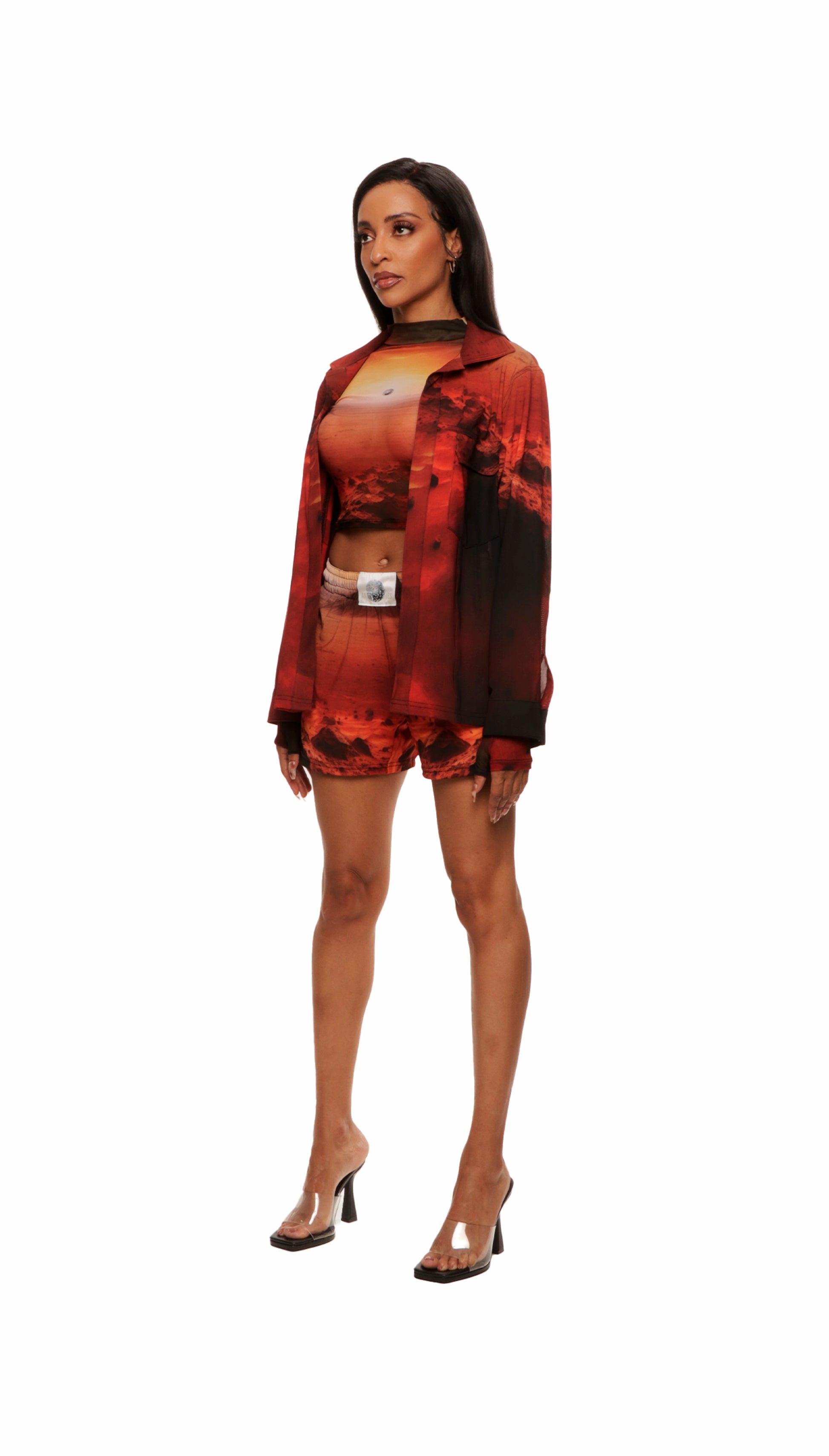 Woman who looks like Beyoncé or Aaliyah wears a cosmic sunset printed long sleeve button up shirt with snaps, side view