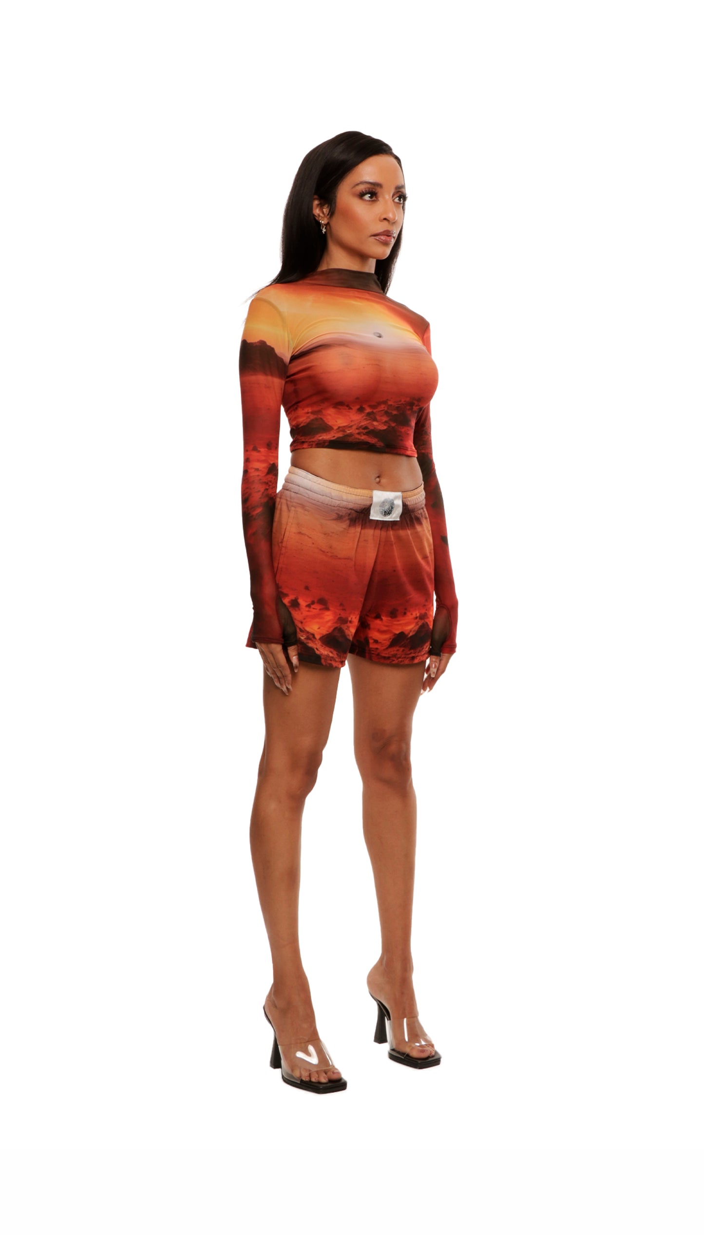 Side view of woman who looks like Beyoncé or Aaliyah wears cosmic Mars sunset printed mesh short basketball shorts QR logo detail