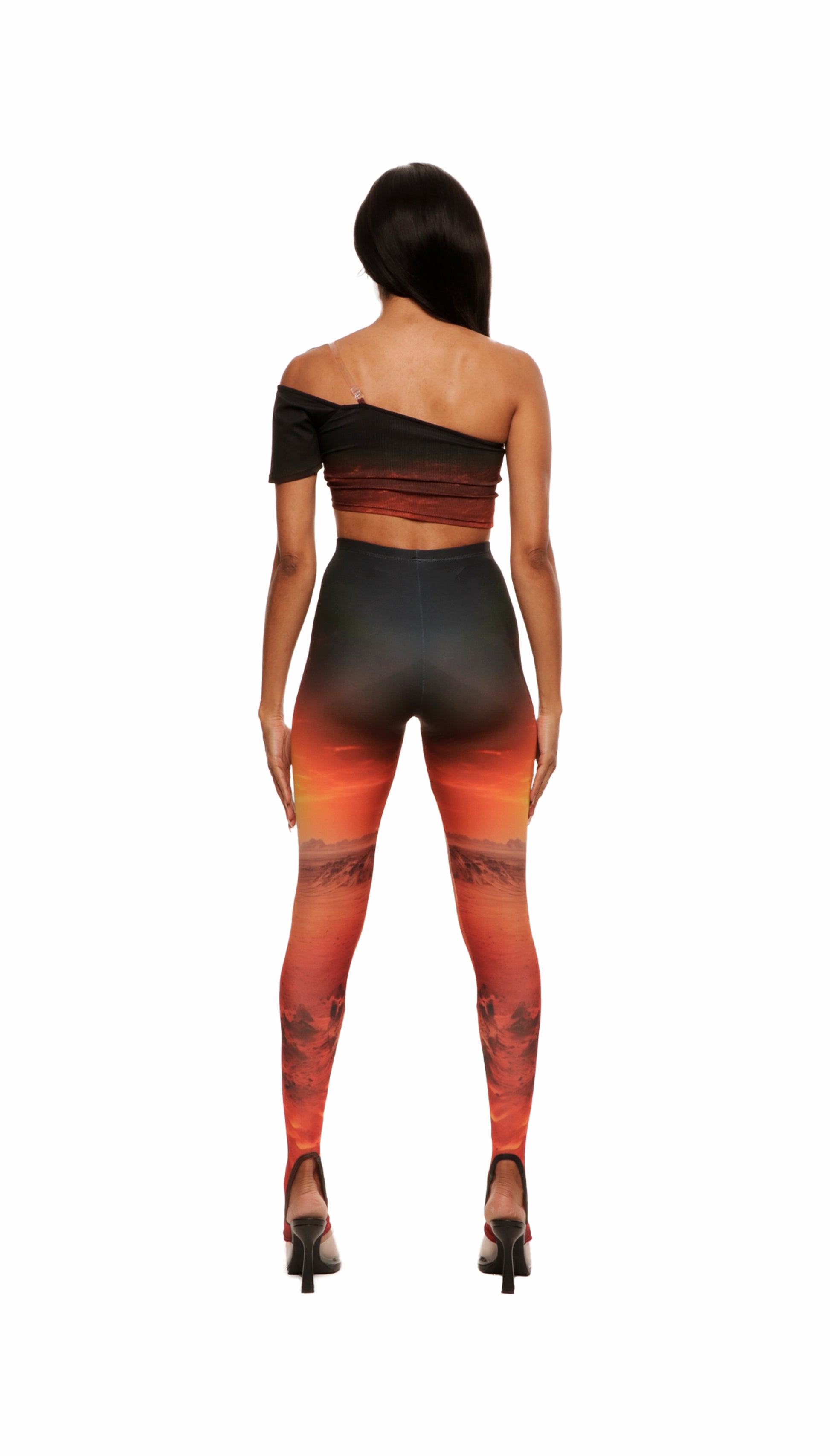Backside of woman who looks like Beyonce or Aaliyah wears sunset printed jersey leggings with cutout details in the front attached with snaps and heel cutout
